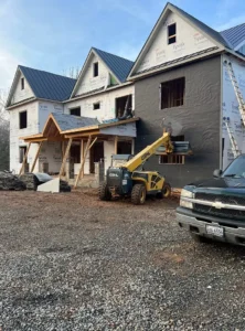 Close-up of a new gable end on a house with light blue vertical board-and-batten style siding and decorative white trim