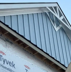Large residential building under construction with multiple gable ends, dark gray roof