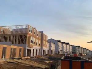 Row of townhouses under construction at sunset, with exposed wood framing